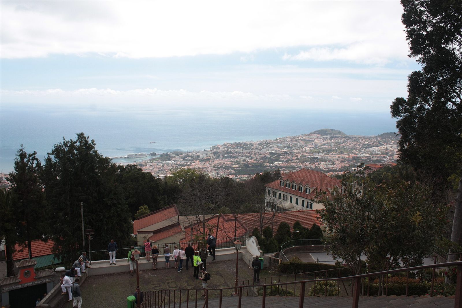 Uitzichtterras in Monte met toeristen die uitkijken over de roodgedekte huizen van Funchal en de kustlijn eronder