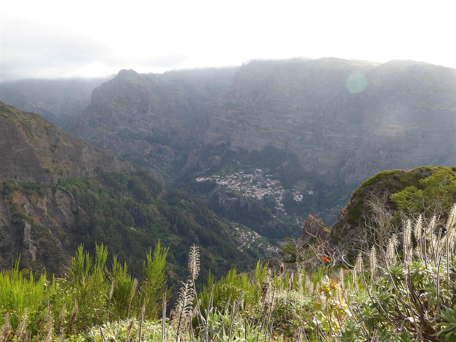 Diep dal in het binnenland van Madeira met een klein dorp tussen steile, in wolken gehulde kliffen