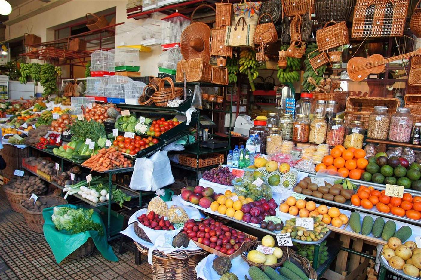 Obst- und Gemüsestand mit darüber hängenden Flechtkörben im Mercado dos Lavradores, Funchal, Madeira