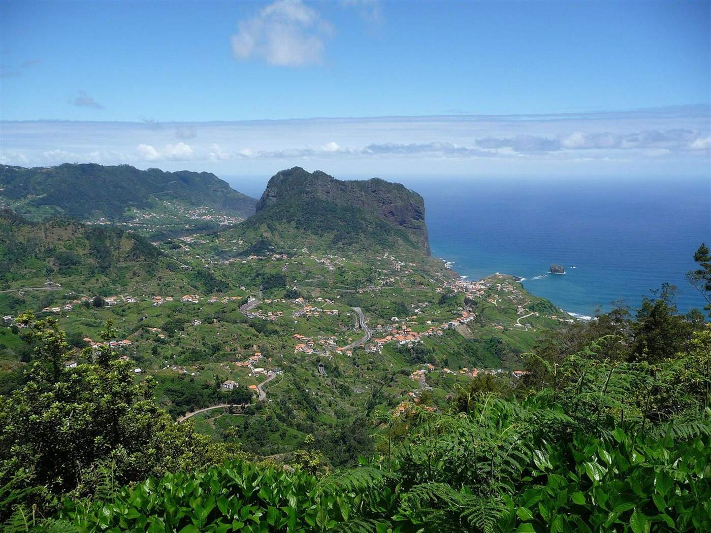 Penha d'Águia erhebt sich über Porto da Cruz an der Nordküste Madeiras, darunter das Dorf und sein terrassiertes Tal, dahinter der Atlantik